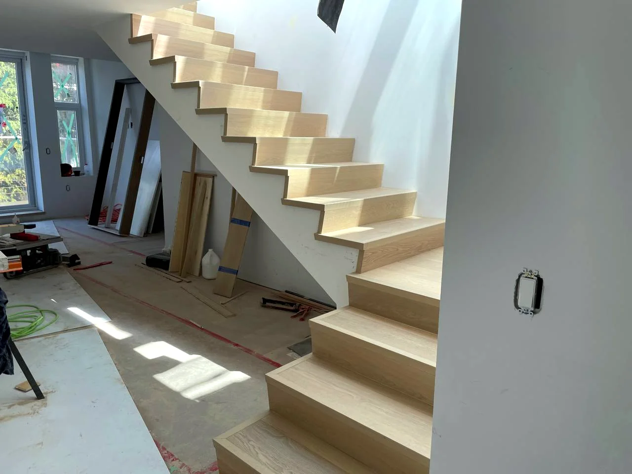 Finished hardwood stair installation with matching protected flooring